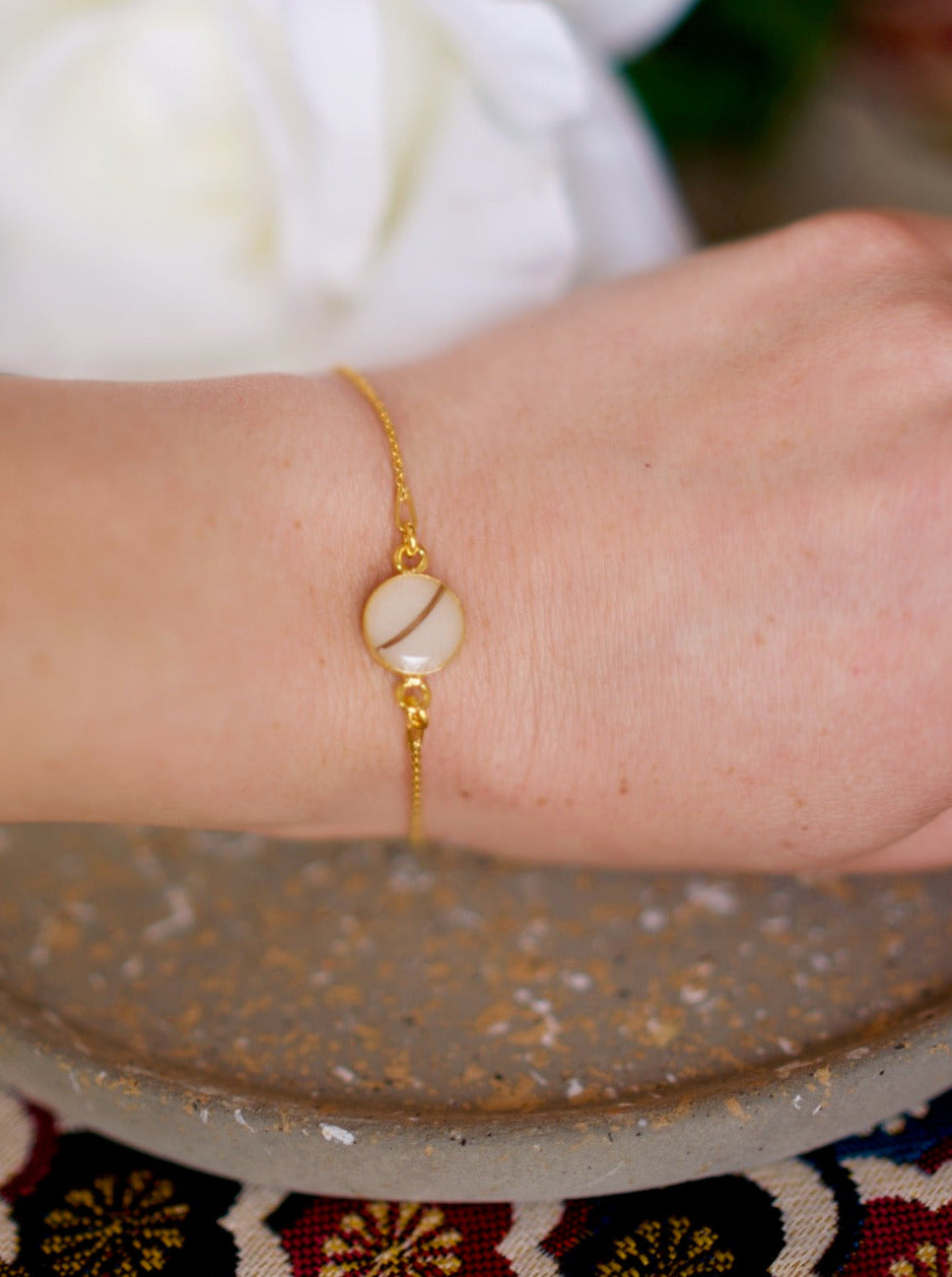 un bracelet en argent 925 plaqué or avec une perle lacté et mèche de cheveux d'un enfant dans un cabochon rond de 1 cm de diamètre